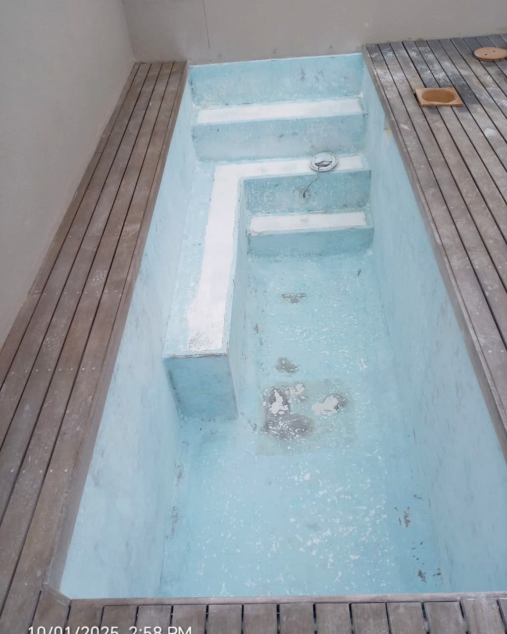 Stanford's Cove pool before revamp — stained, patched concrete with a failing surface
